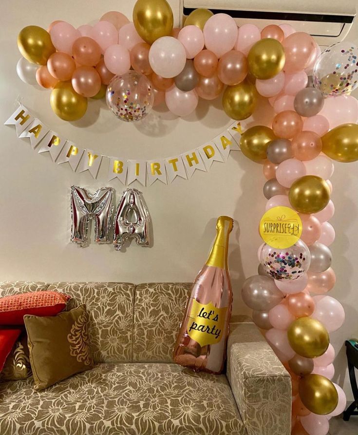 a couch sitting under a balloon arch filled with balloons and confetti on top of it