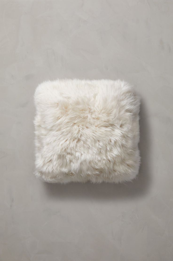 a white furry pillow sitting on top of a wall