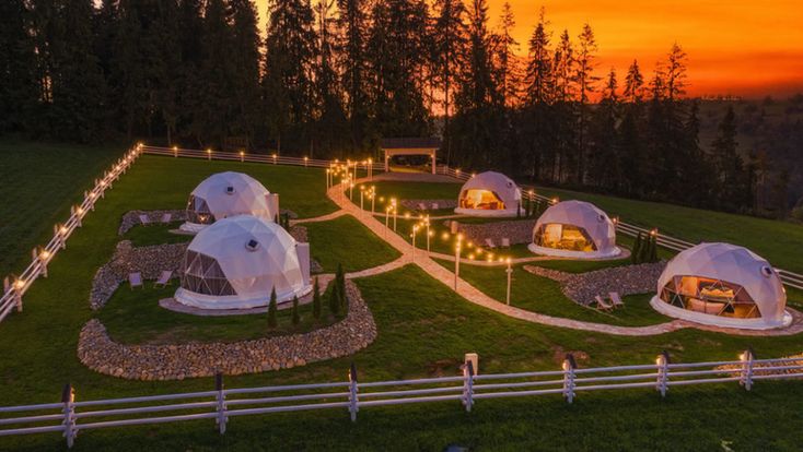 an aerial view of several domes lit up in the evening with lights shining on them