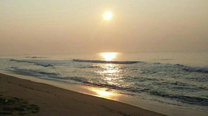 the sun is setting over the water at the beach