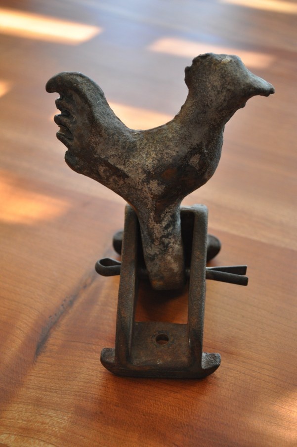 a small metal rooster on a wooden table