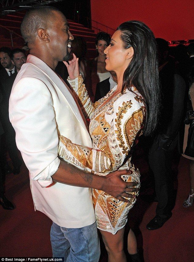 a man and woman standing next to each other in front of a red wall at a party