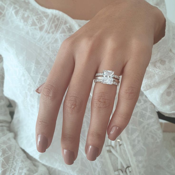 a woman's hand with a ring on it and her wedding band in the middle