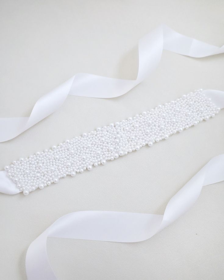 A statement sash is encrusted with beautiful pearls attached on bridal white double-faced satin ribbon. This classic pearly belts creates a romantic finishing touch to your bridal gown, bridesmaids and flower girls, or as hair accessories. DETAIL:Adult Size 108"Kids Size 78"Applique size: 12" length, 2" wideHANDMADE IN USAIMPORTED MATERIALS Elegant Satin Bridal Accessories For Wedding, Elegant Ribbon Bridal Belt For Wedding, Elegant Bridal Belt With Satin Bow For Wedding, White Adjustable Wedding Sashes, Elegant Bridal Accessories With Pearl Embroidery For Ceremony, White Satin Bridal Accessories For Formal Occasion, Adjustable Ribbon Wedding Sashes, Elegant Bridal Belt With Satin Bow For Bridesmaid, Elegant Bridal Belt With Satin Bow For Party