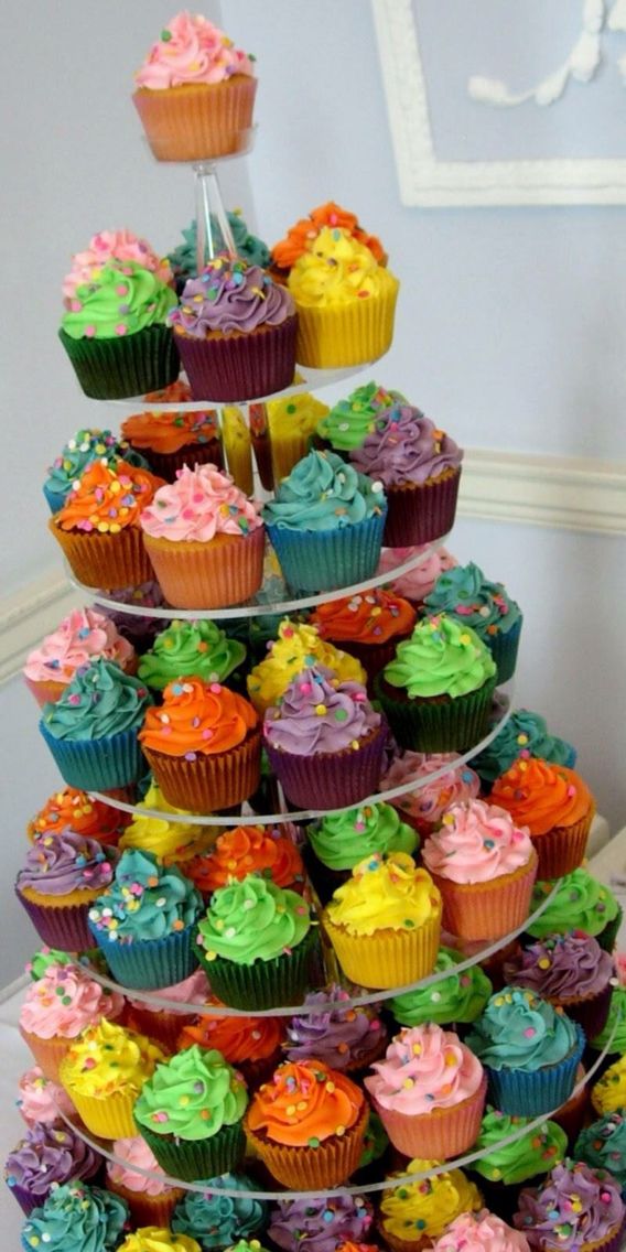 a multi - tiered cupcake display is decorated with colorful frosting