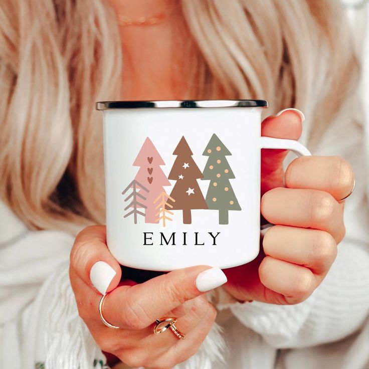 a woman holding a white coffee mug with trees on it and the words family printed on it