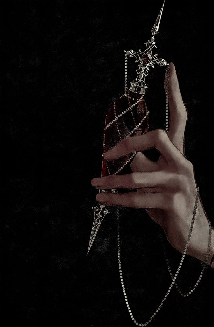 a woman's hand holding a piece of cloth with chains and pearls on it