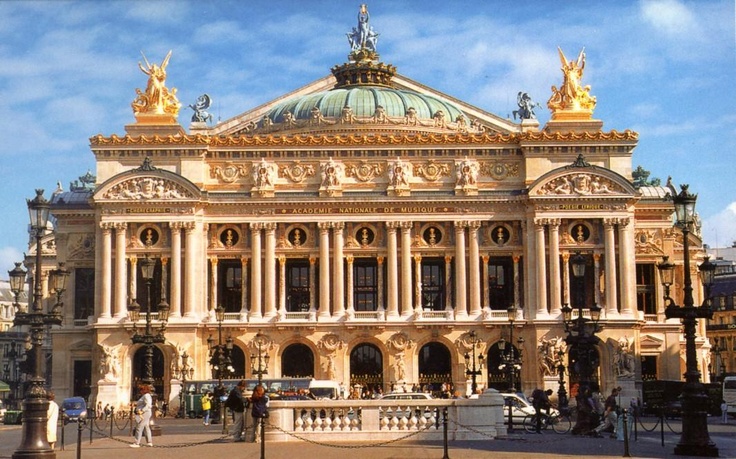 an ornate building with statues on the front and sides, surrounded by blue skies in the background