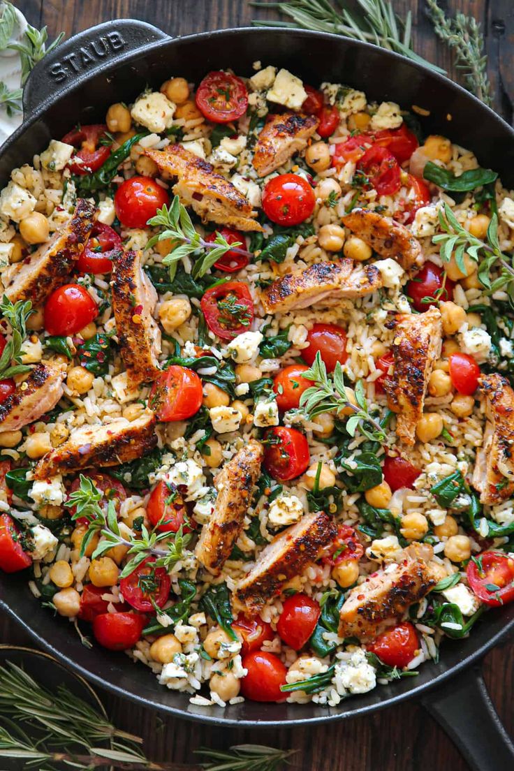 a skillet filled with chicken, tomatoes and chickpeas