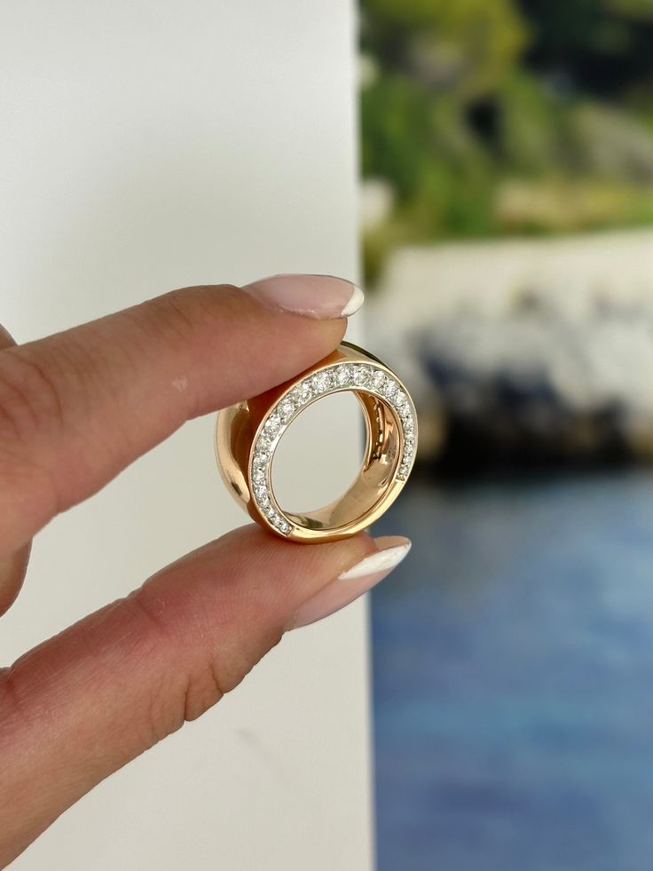 a woman's hand holding a gold ring with diamonds on the outside and inside