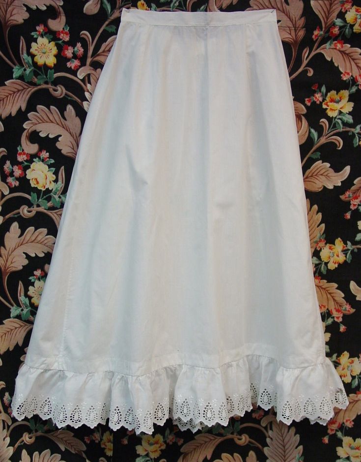 This is a sweet antique Edwardian petticoat. It is white cotton and has an eyelet ruffle at the bottom. It has a placket and pearl button at the waist. I have shown one little hole in the ruffle and there is a little wear here and there on the ruffle but very little and nothing distracting. I have also shown one pinhole near the ruffle. It is a petite size with a 22" waist and the length is 28". It has been freshly washed and ironed and has no spots. I combine shipping and am happy to provide a shipping quote to international shoppers. Thanks for visiting... White Regency Style Petticoat With Ruffles, Regency Style Ruffled Petticoat For Daywear, Daywear Ruffled Petticoat, White Cotton Petticoat With Attached Cancan, Victorian White Ruffled Petticoat, Victorian White Petticoat With Ruffles, White Regency Style Cotton Petticoat, Daywear Cotton Petticoat With Lace Trim, Cotton Petticoat With Lace Trim For Daywear