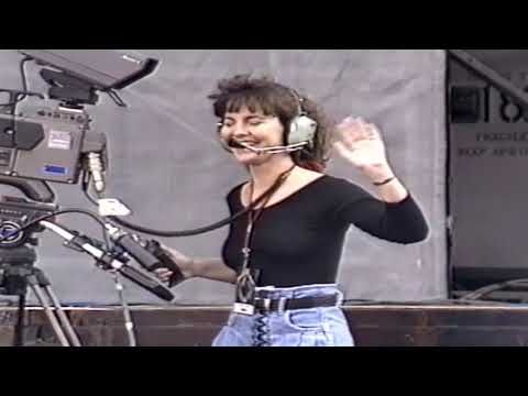 a woman with headphones on standing in front of a camera and microphone, talking to someone