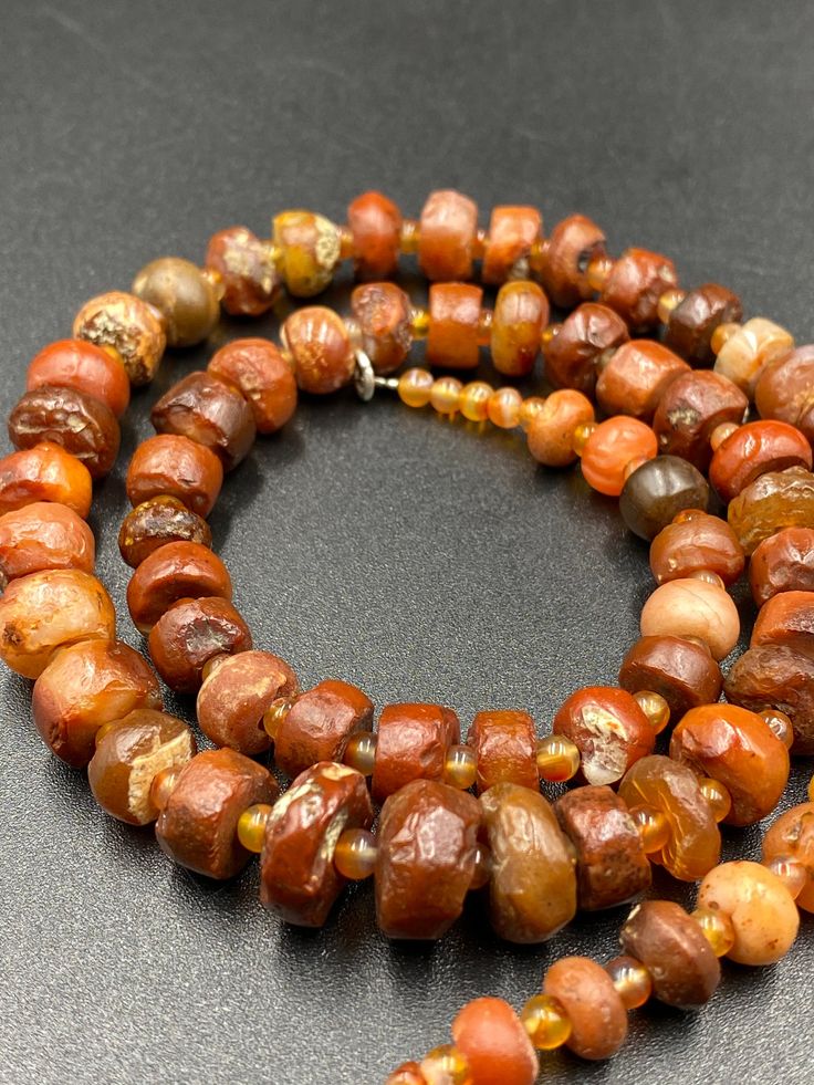 The beautiful carnelian mala necklace along with some small carnelian beads spacers The age of this beads are more than 2000 years old carnelian and old agate was used in ancient times in prayer mala and in jewelry necklaces we provide fast and free shipping service world wide Brown Agate Beads For Jewelry Making, Brown Gemstone Beaded Necklace, Artisan Brown Agate Beads And Cabochons, Amber Natural Stones Beads For Jewelry Making, Amber Beads For Jewelry Making With Natural Stones, Earthy Agate Beaded Necklaces With Round Beads, Unique Amber Carnelian Beaded Necklaces, Amber Natural Stones For Jewelry Making, Brown Gemstone Beaded Necklace With Round Beads