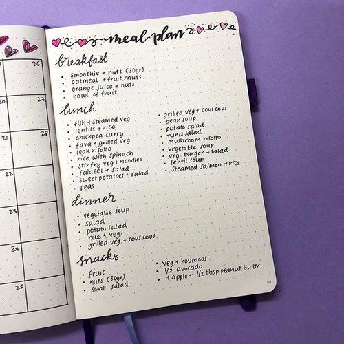 an open planner with hearts on it sitting on a purple table next to a cup of coffee