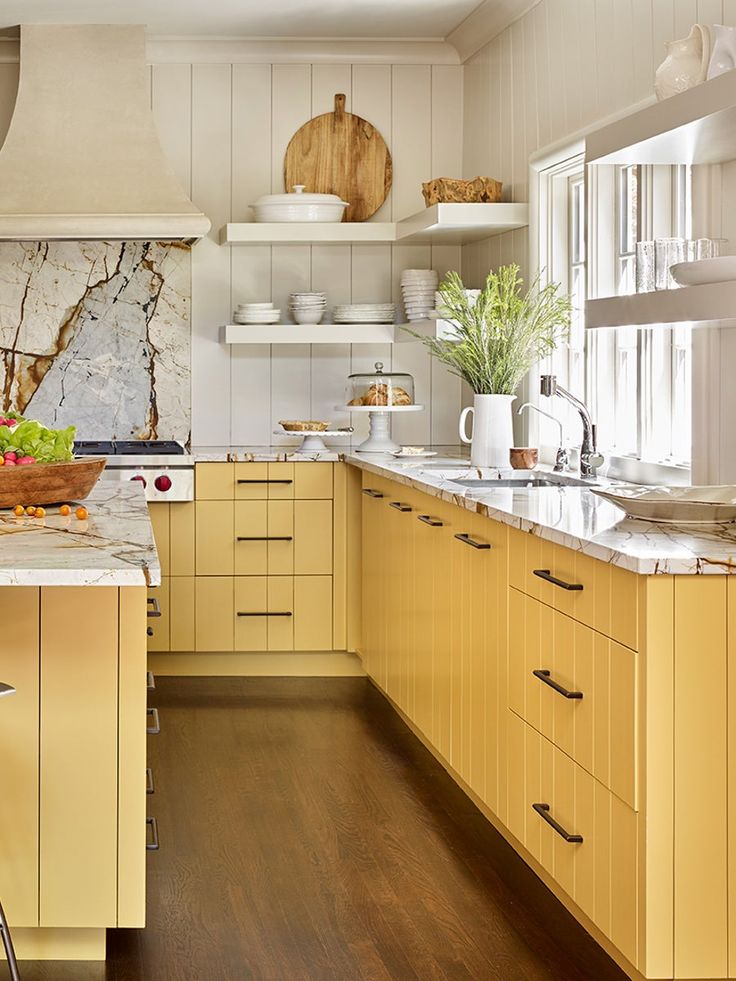 a kitchen filled with lots of counter top space and yellow cupboards next to a wooden floor