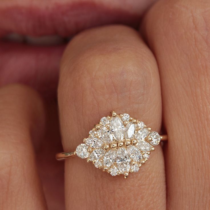 a woman's hand with a diamond ring on top of her finger and the other hand holding an engagement ring