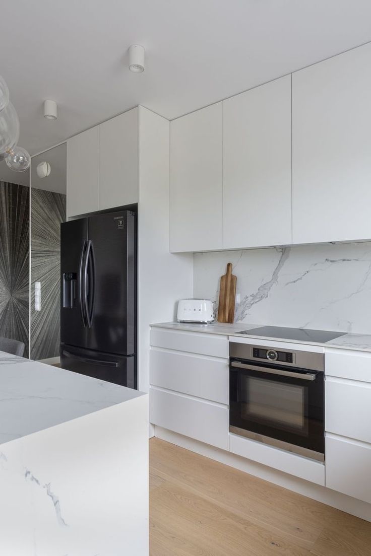 a kitchen with marble counter tops and white cabinets, along with a black refrigerator freezer