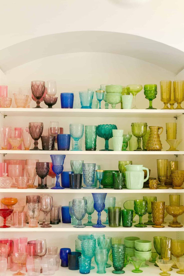 many different colored glass cups are on shelves