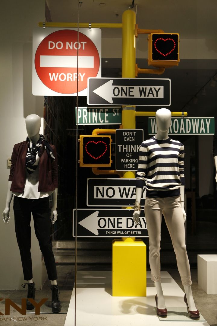 two mannequins dressed in black and white standing next to street signs