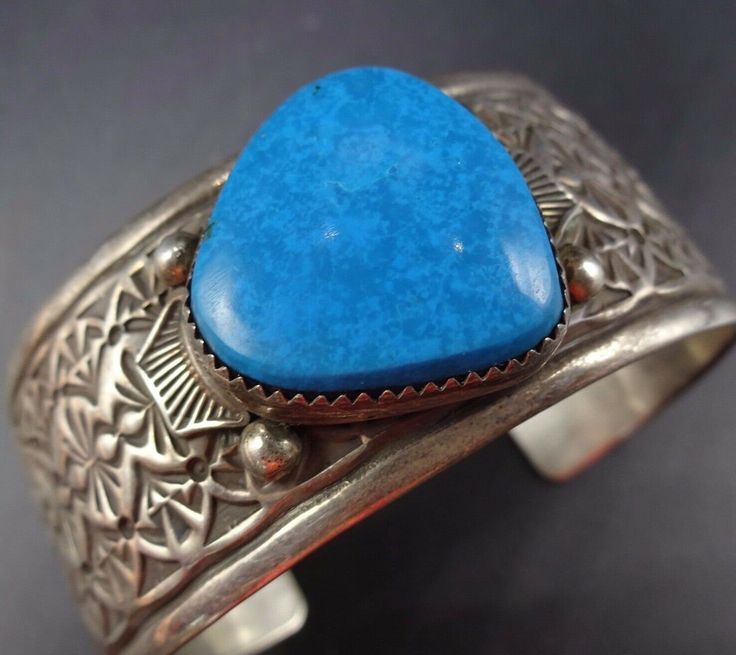 "VINTAGE NAVAJO BRACELET DESCRIPTION: This cuff features a gorgeous specimen of high blue turquoise on a cuff with intricate stamp work. The gemstone is secure in smooth bezel, on a foundation of heavy gauge vintage sterling silver. This bracelet will be a cherished addition to your collection of fine vintage Native American jewelry. MEASUREMENTS: Interior of the cuff measures 5 3/4\" with an additional 1 1/4\" slightly adjustable gap. Total circumference: 7\" Measures 2 1/2\" straight across th Bohemian Blue Stamped Bracelets, Bohemian Stamped Blue Bracelets, Blue Stamped Bohemian Bracelets, Southwestern Blue Cuff Bracelet As Gift, Southwestern Style Stamped Blue Bracelets, Vintage Blue Bangle Bracelets, Blue Vintage Stamped Jewelry, Vintage Stamped Blue Jewelry, Unique Blue Cuff Bracelets