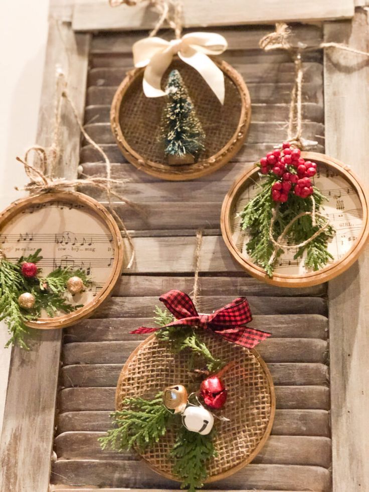 three christmas wreaths hanging from the side of a wooden window sill with pine cones and red berries