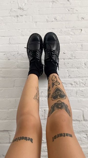 the legs and ankles of a woman with tattoos on her body, wearing black sneakers