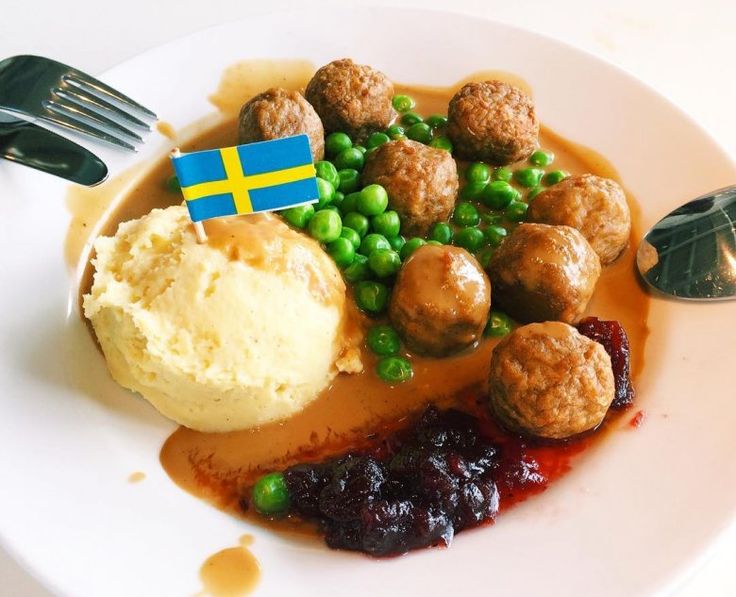 a white plate topped with meatballs and mashed potatoes next to a fork on a table