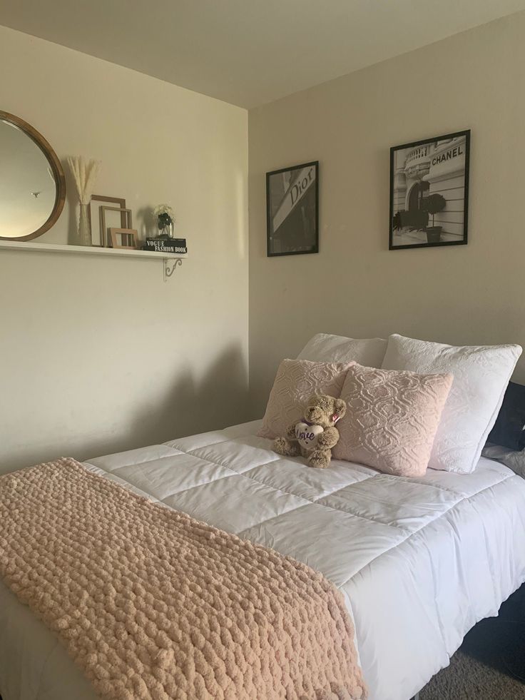 a bed with white sheets and pillows in a bedroom next to pictures on the wall