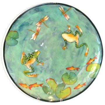 a green plate with goldfish and dragonflies on it's sides, in the water