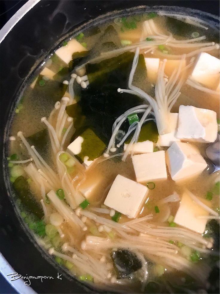 soup with tofu, noodles and green onions in a pot on the stove top