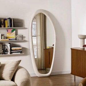 a living room filled with furniture and a large white mirror on the wall above it