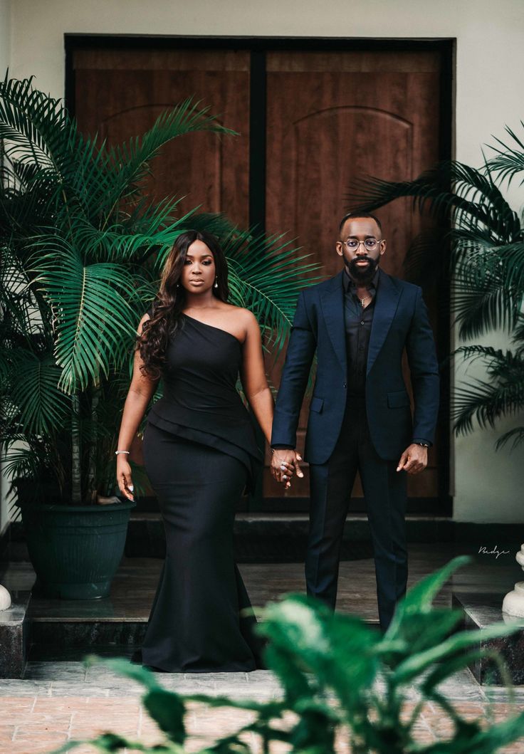 a man and woman holding hands in front of a door with palm trees behind them