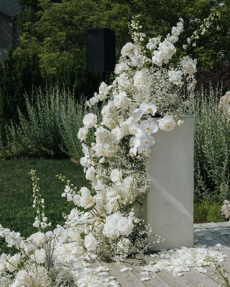 an arrangement of white flowers and greenery in a garden