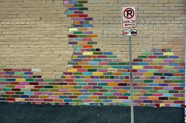 a brick wall with a no parking sign painted on it's side next to a street sign