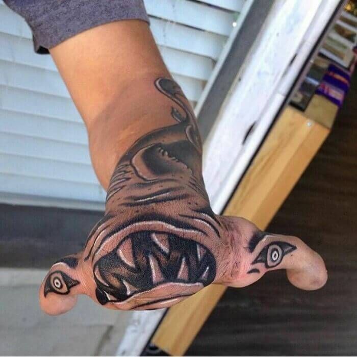 a person with a tattoo on their hand that has an image of a dog's mouth