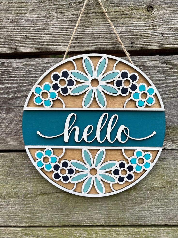 a wooden sign that says hello with flowers on it and the word hello painted in blue