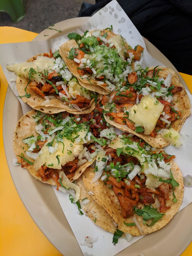 some tacos are sitting on a paper plate