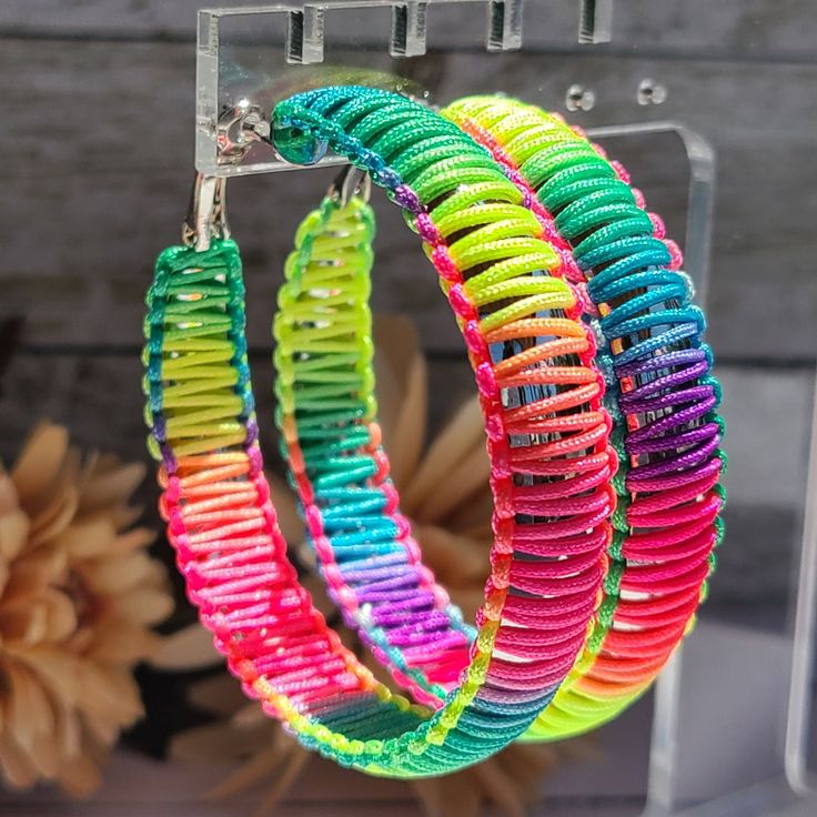 "Get ready to turn heads and embrace the vibrant spirit of the 80's with these lively multicolor threaded hoop earrings. The neon threads add an electrifying burst of color, making them the perfect accessory for parties, music festivals, and any occasion where you want to express your unique personality. Crafted with care and attention to detail, these earrings showcase a perfect blend of retro charm and contemporary style. The threaded design adds texture and depth, creating a dynamic and playful look that complements a variety of outfits. The 2.25\" diameter of these hoops ensures that they make a statement, drawing attention to your face and accentuating your features. The 11mm width adds substance and presence, making them stand out from traditional hoops. Designed with a leverback clo Multicolor Bohemian Hoop Earrings For Spring, Multicolor Summer Festival Hoop Earrings, Multicolor Hoop Earrings For Summer Festival, Multicolor Small Hoop Jewelry For Spring, Trendy Multicolor Hoop Earrings For Festivals, Multicolor Hoop Earrings For Summer, Colorful Small Hoop Earrings For Summer, Handmade Multicolor Hoop Earrings For Spring, Adjustable Multicolor Hoop Earrings