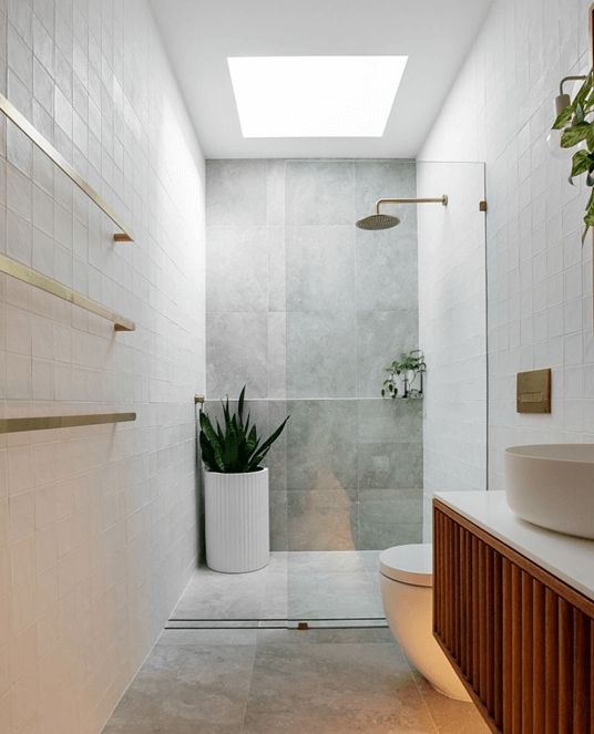 a bathroom with a white toilet sitting next to a plant in a vase on the counter