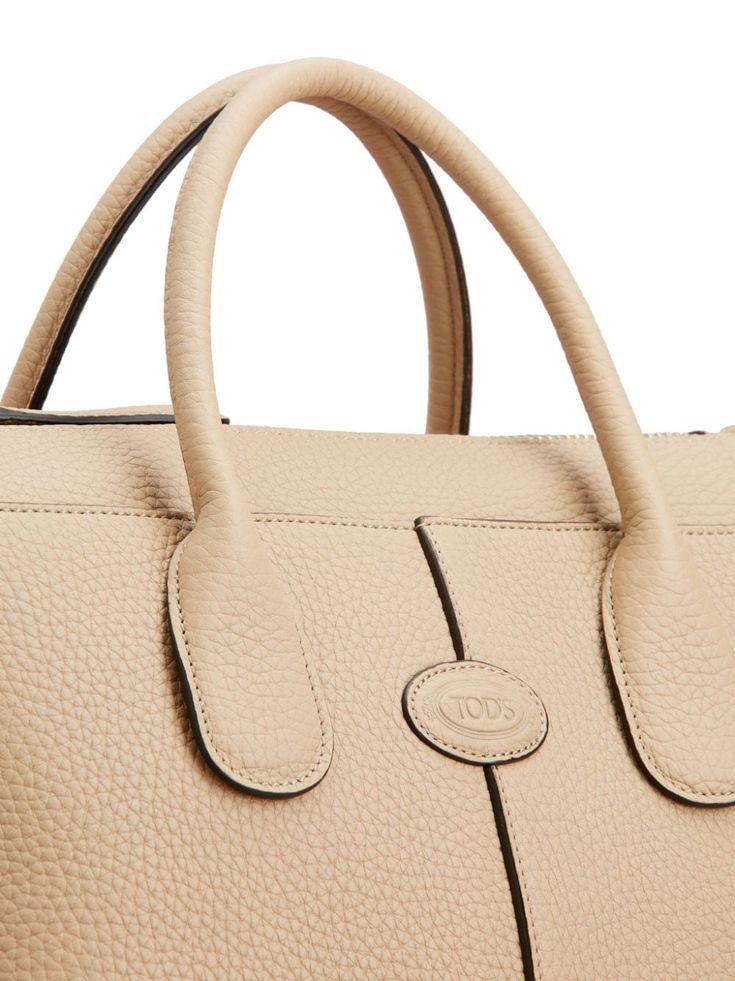 Find TOD'S Di Leather Tote Bag on Editorialist. This Tod's tote bag is crafted from calfskin with a pebbled texture. The bag features a debossed logo to the front, two rolled top handles, an adjustable detachable shoulder strap, and a top zip fastening. The main compartment contains an internal zip-fastening pocket. This tote bag is small in size and has a top handle. Beige Pebbled Leather Shoulder Bag With Top Handle, Beige Pebbled Leather Top Handle Shoulder Bag, Beige Pebbled Leather Satchel With Double Handle, Beige Pebbled Leather Top-handle Satchel, Beige Pebbled Leather Top Handle Satchel, Soft Pebbled Leather Bag With Top Handle, Soft Pebbled Leather Top Handle Bag, Luxury Pebbled Leather Satchel Bag, Designer Beige Calf Leather Bag