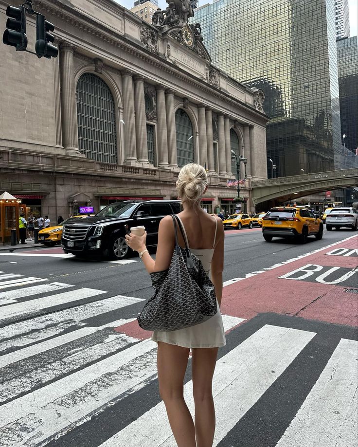 a woman is walking across the street with her cell phone in her hand while looking at traffic