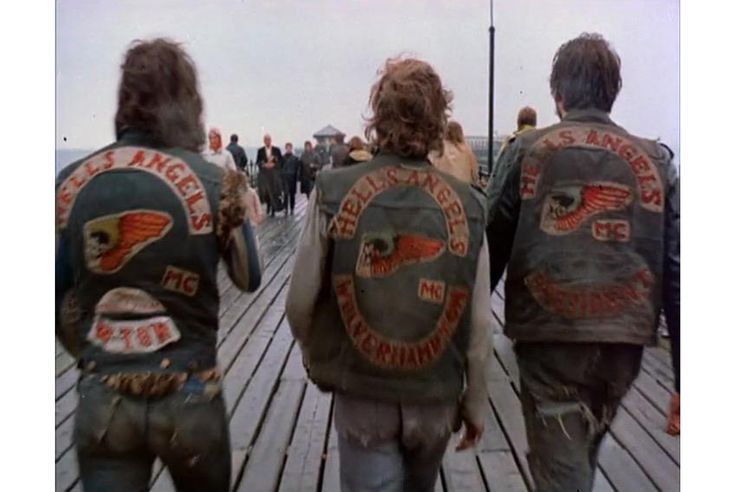 three people wearing leather jackets walking on a pier