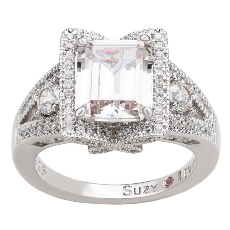 This beautiful Suzy Levian ring features an emerald cut white cubic zirconia center stone, framed with white round cut cubic zirconia's in a pave halo and sides stones. This beautiful ring has a butterfly detail on each side of the basket of the ring. This magnificent ring crafted of white sterling silver with a high polish finish highlights the marvelous purple cubic zirconia center stone. This ring is designed by Suzy Levian with a message. By creating jewelry that is beautiful inside and out, Levian Ring, Levian Rings, Pave Engagement Ring, Beautiful Inside And Out, Ring Crafts, Creating Jewelry, Beautiful Ring, A Butterfly, Emerald Cut