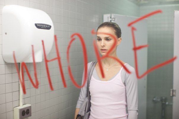 a woman standing in front of a urinal with graffiti on the wall behind her