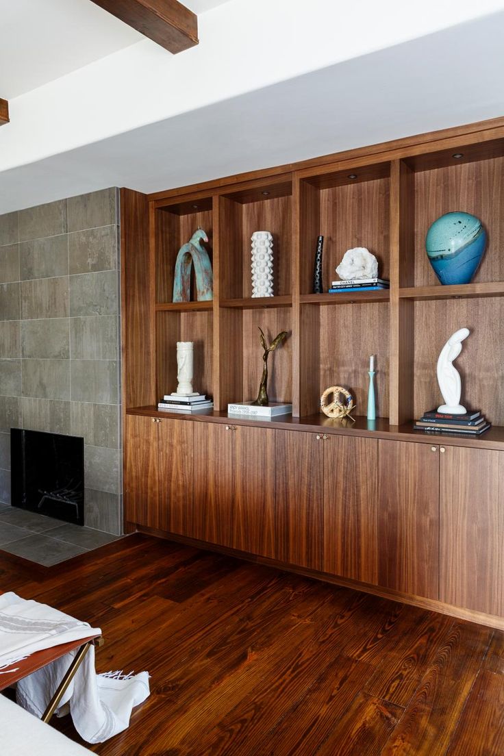 a living room filled with furniture and wooden shelves next to a fire place on top of a hard wood floor