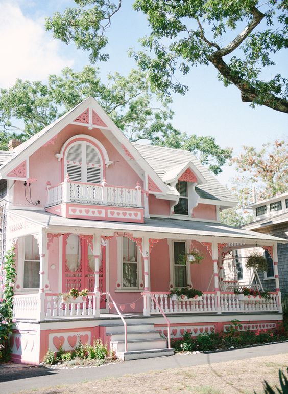 a pink house with white balconies on the porch