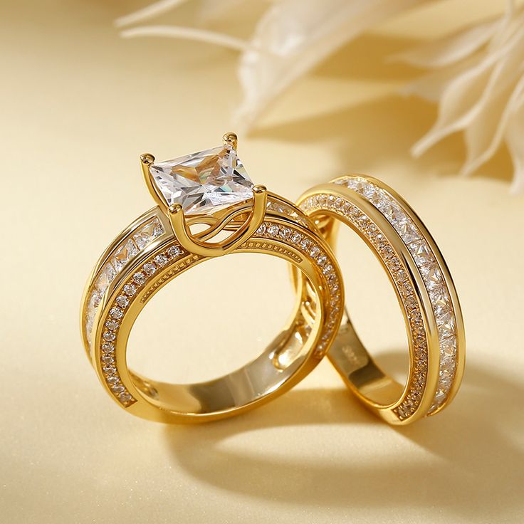 two gold wedding rings with white diamonds on the top and one diamond in the middle