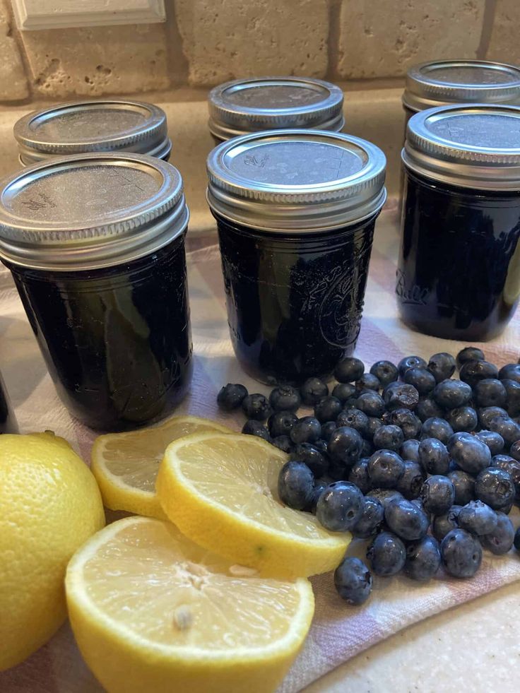 lemons, blueberries and jars of jam sit on a towel next to sliced lemons