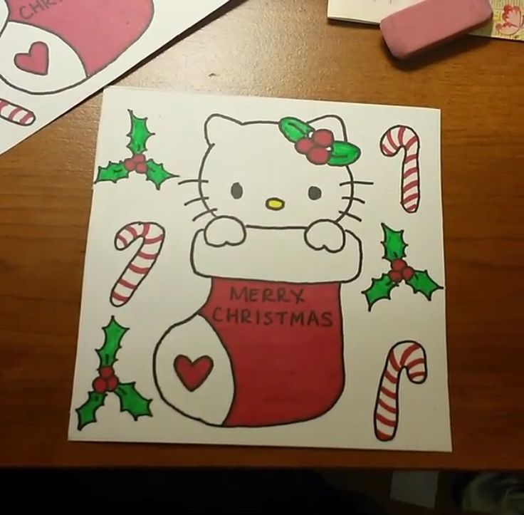 a hello kitty christmas card with candy canes and candies on the table next to it