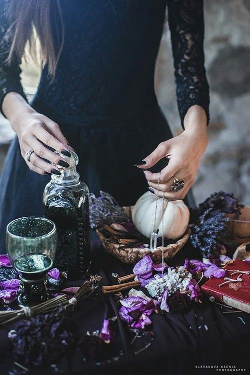 a woman in black dress pouring liquid into a glass jar on top of a table